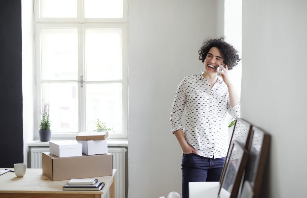 Laughing young woman on the phone in home office